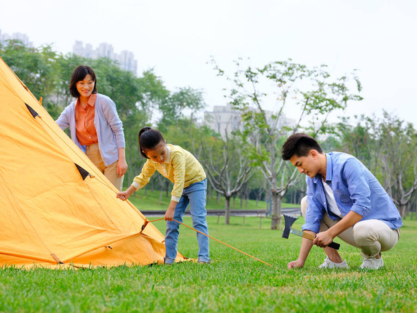 A happy family of three set up tents outdoors - Fotografie, Obrázek