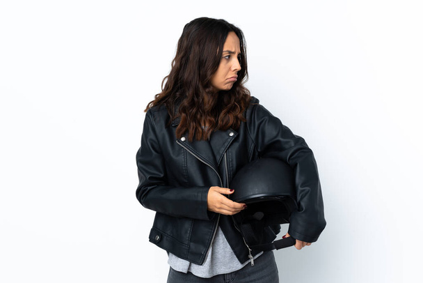 Young woman holding a motorcycle helmet over isolated white background portrait - Valokuva, kuva
