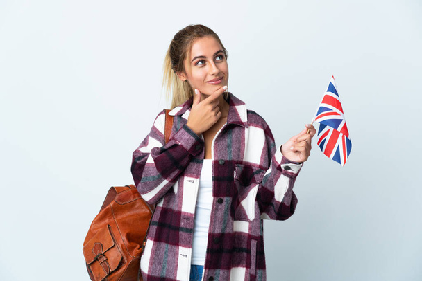 白地にイギリス国旗を掲げた若い女性が笑顔で見上げている - 写真・画像