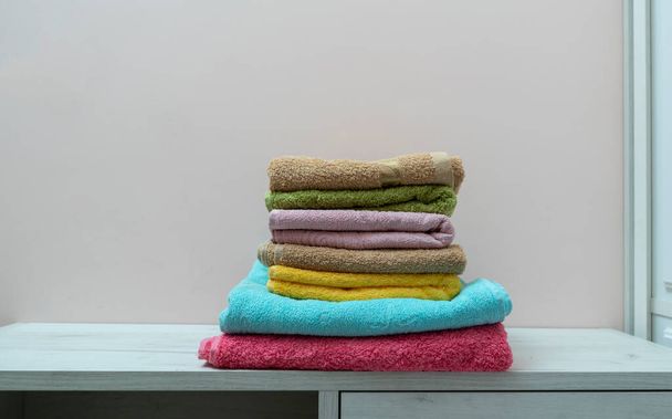 una pila de nuevas toallas limpias de color fresco textil en el estante en la lavandería - Foto, imagen