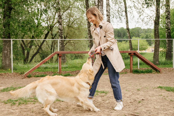 The girl the owner of the dog breed golden retriever plays with her on the playground for walking the dogs - Photo, Image