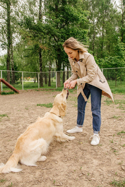The girl the owner of the dog breed golden retriever plays with  - Fotografie, Obrázek