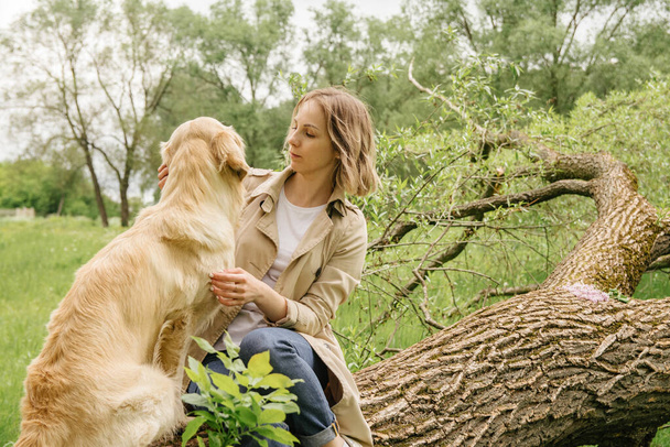 Milenka sedí a mazlí se se svým psem ze Zlatého Re - Fotografie, Obrázek