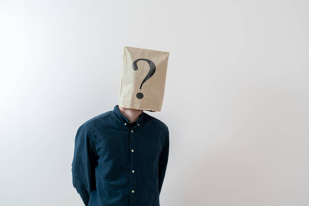 persona con una bolsa de papel en la cabeza con signo de interrogación, signo de problema - Foto, Imagen