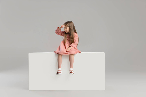 Portrait of little Caucasian cute girl posing isolated over gray studio background. - Фото, изображение