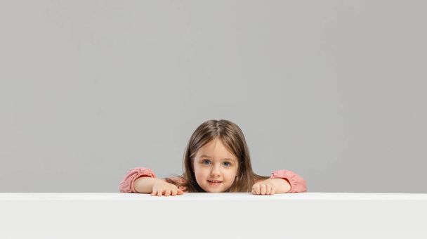 Portrait of little Caucasian cute girl posing isolated over gray studio background. - Foto, Imagem