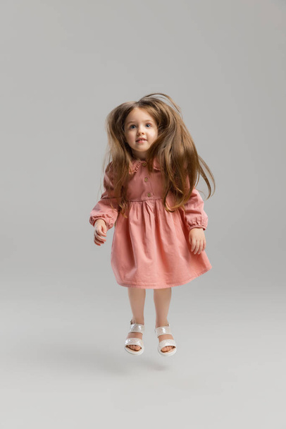 Portrait of little Caucasian cute girl posing isolated over gray studio background. - Valokuva, kuva