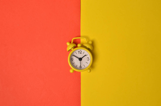 Ρολόι συναγερμού απομονώνονται σε κίτρινο και κόκκινο φόντο - Φωτογραφία, εικόνα