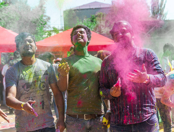 много людей на цветном празднике, цветные лица людей, цветовой фестиваль в Индии - Фото, изображение