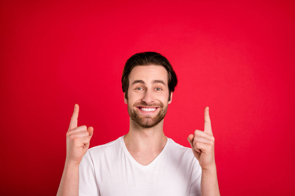 Photo of cheerful happy young man point fingers up empty space good mood isolated on red color background - Photo, Image