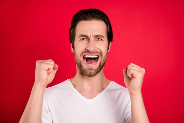 Photo of amazed crazy happy man raise fists winner champion good mood isolated on red color background - Фото, изображение