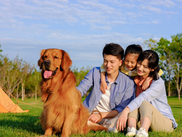 Glückliche dreiköpfige Familie mit Hund im Park - Foto, Bild