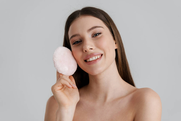 Happy shirtless nice girl smiling and using powder sponge isolated over white background - Foto, Imagem