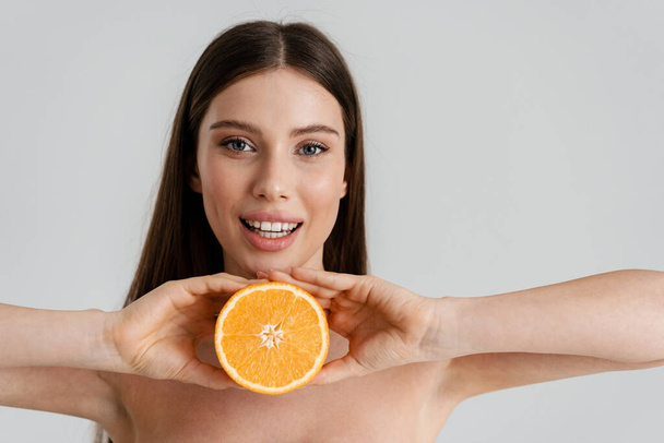 Happy shirtless girl smiling while posing with orange isolated over white background - Zdjęcie, obraz
