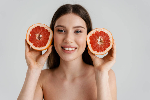 Happy shirtless girl smiling while posing with grapefruit isolated over white background - Photo, image