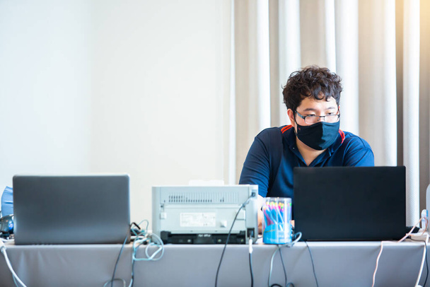 マスクをしたアジア系のスピーカーが会議室で講演を行う。ビジネス会議でのウイルスCovid-19の拡散を防ぐ. - 写真・画像