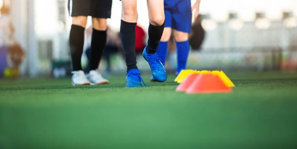 トレーニングのための緑の人工芝にジョギング男の子サッカー選手の足に選択的な焦点。サッカー・サッカーアカデミー. - 写真・画像