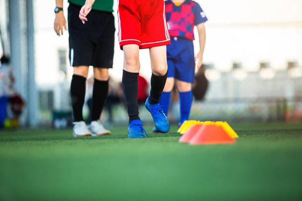 Selectieve focus op been van jongen voetballers joggen op groene kunstgras voor training. Voetbal of voetbal academie. - Foto, afbeelding