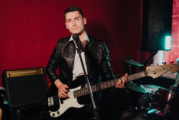 Jovem hipster masculino gravando novos sons em estúdio enquanto toca guitarra electro e canto - Foto, Imagem