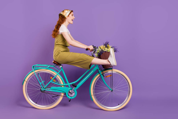 Профиль боковой вид портрет довольно модный веселый смешной девушки цикл езды быстро без ног изолированы на фиолетовый фиолетовый цвет фона - Фото, изображение