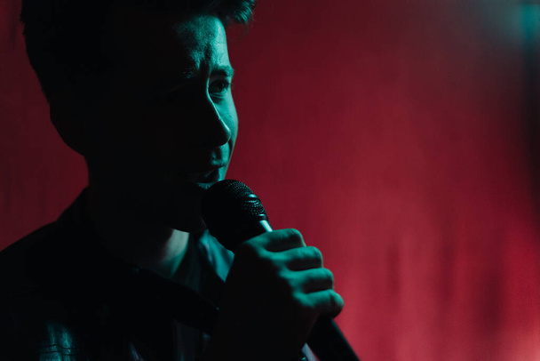 Человек в кожаной куртке выступает на темной сцене в клубе - Фото, изображение