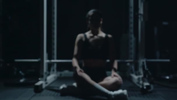 Спортивна кавказька жінка сидить сама після роботи в темному спортзалі.. - Кадри, відео