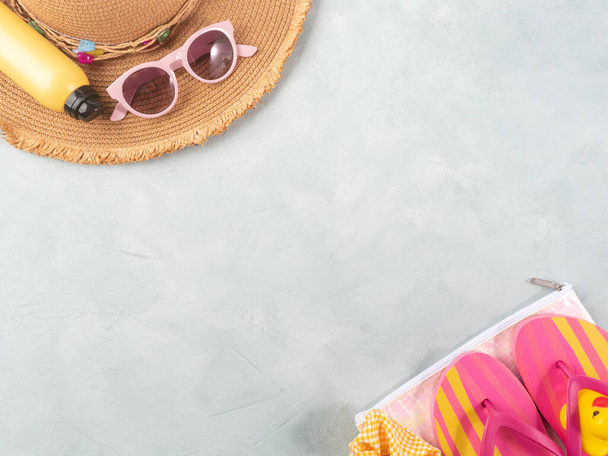 Accesorios de vacaciones de verano mar. Sombrero de paja, chanclas, spray solar, gafas de sol sobre fondo de piedra. - Foto, imagen