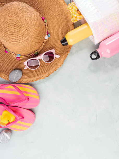 Аксессуары для летнего отдыха. Соломенная шляпа, шлепанцы, солнечный спрей, солнцезащитные очки на каменном фоне. - Фото, изображение