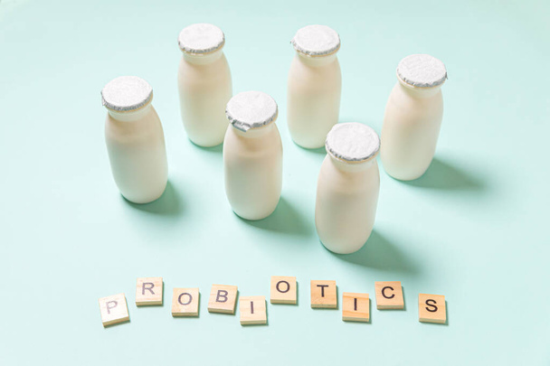 Piccole bottiglie con probiotici e prebiotici latticini su sfondo blu. Produzione con additivi biologicamente attivi. Fermentazione e dieta cibo sano. Bio yogurt con microrganismi utili - Foto, immagini