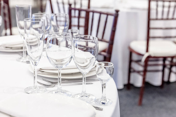 Fantazyjny zestaw stołowy do kolacji z serwetkami w restauracji, luksusowe tło wnętrza. Wedding eleganckie dekoracje bankietowe i przedmioty do żywności zorganizowane przez obsługę cateringową na białym stole obrus - Zdjęcie, obraz