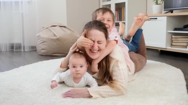 Feliz família sorrindo e rindo com as crianças relaxando no tapete na sala de estar. Paternidade, felicidade das crianças e relacionamento familiar - Filmagem, Vídeo