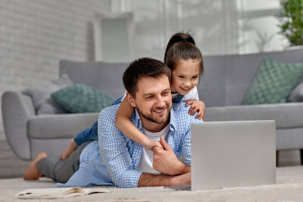 little child girl and handsome father using laptop - Фото, изображение