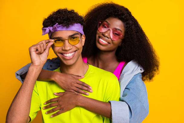Portrait of attractive cheerful affectionate funky couple partners embracing isolated over bright yellow color background - Foto, Imagem