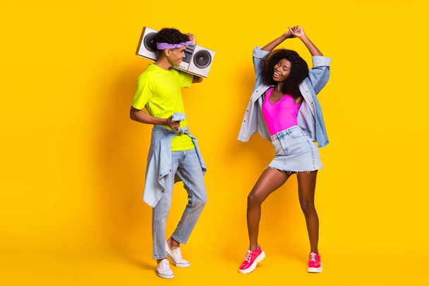 Full length body size view of handsome beautiful cheerful couple dancing carrying boombox isolated over bright yellow color background - Photo, image