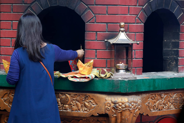 Guan Di templo taoísta chinês. Mulher queimando ofertas de papel joss no forno. Kuala Lumpur. Malásia.  - Foto, Imagem