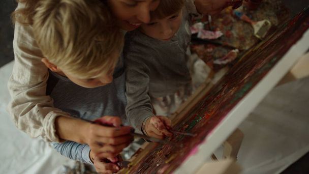 Feliz familia pintando juntos en el interior. Niños creando obras de arte en la escuela. - Foto, Imagen