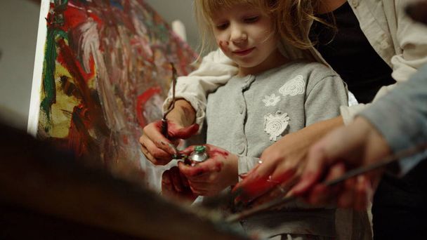 Unbekannte Frau verbringt Zeit im Atelier. Konzentriertes Mädchen, das drinnen Farbe quetscht. - Foto, Bild
