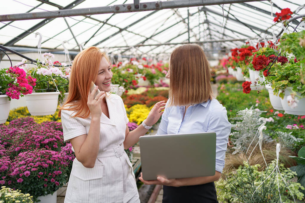 Dos mujeres de negocios conversando mientras visitan el invernadero - Foto, Imagen
