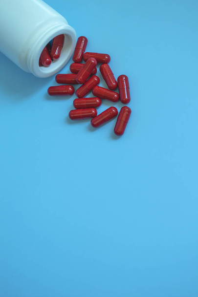Medyczna rurka koncepcyjna z pigułkami, kapsułki koloru czerwonego na niebieskim tle. Leki prtiv kovid19 lub witaminy dla odporności. Wyzdrowienie po zakażeniu HIV 19. Suplement diety. - Zdjęcie, obraz