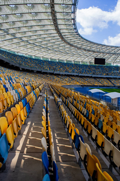 Empty rows of seats in a football olympic stadium with yellow and blue benches - Foto, Imagem