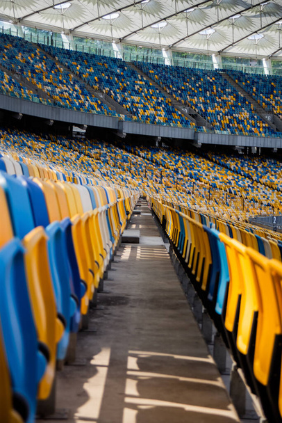 Empty rows of seats in a football olympic stadium with yellow and blue benches - Φωτογραφία, εικόνα