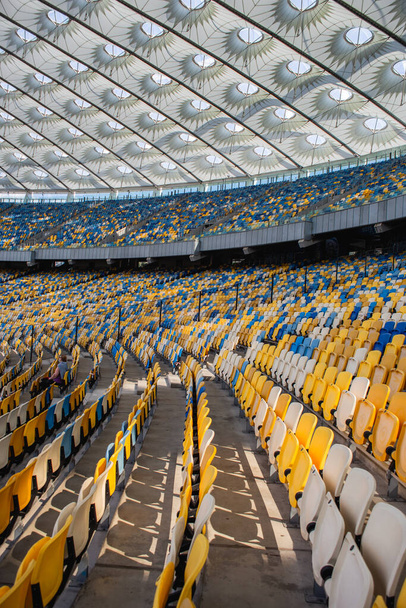 Empty rows of seats in a football olympic stadium with yellow and blue benches - 写真・画像