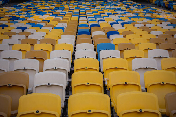 Empty rows of seats in a football olympic stadium with yellow and blue benches - Photo, Image