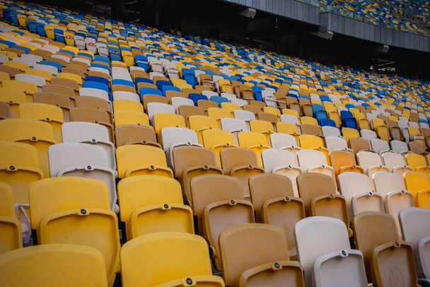 Tyhjät paikat jalkapallon olympiastadionilla, jossa on keltaiset ja siniset penkit - Valokuva, kuva