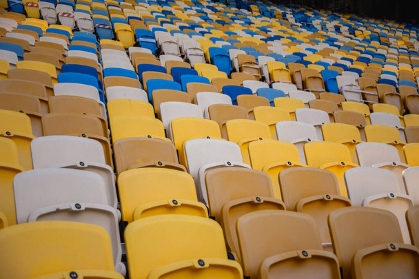Порожні ряди місць на футбольному олімпійському стадіоні з жовто-блакитними лавками
 - Фото, зображення
