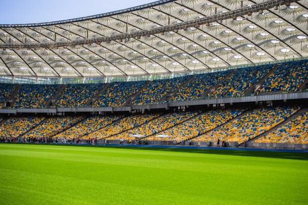 Lege rijen stoelen in een Olympisch voetbalstadion met gele en blauwe banken - Foto, afbeelding