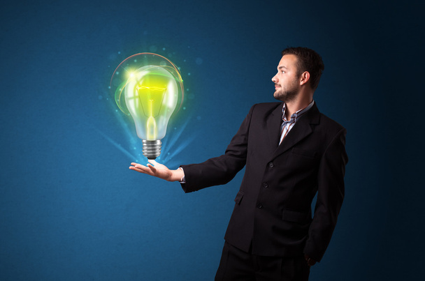 Glowing lightbulb in the hand of a businessman - Foto, Bild