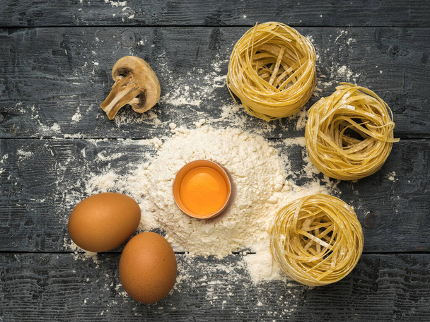 Eggs, flour, mushrooms and pasta on a wooden table. Ingredients for making pasta. - Photo, Image