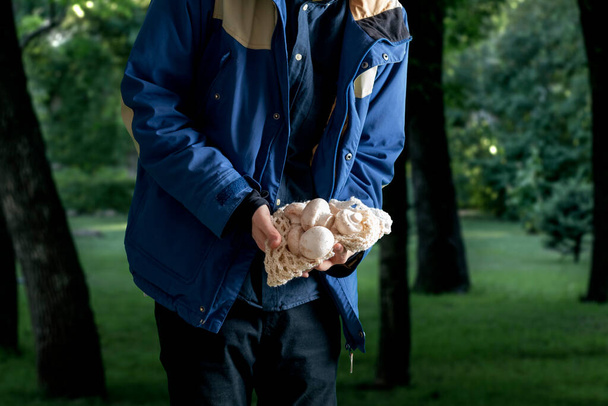 Egy férfi, aki gombát tart az erdőben. gombaszezon összegyűjtése - Fotó, kép