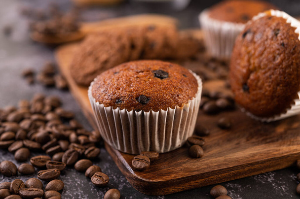 Banana cupcakes that are placed on a wooden plate with coffee grains. Selelctive focus. - Photo, Image